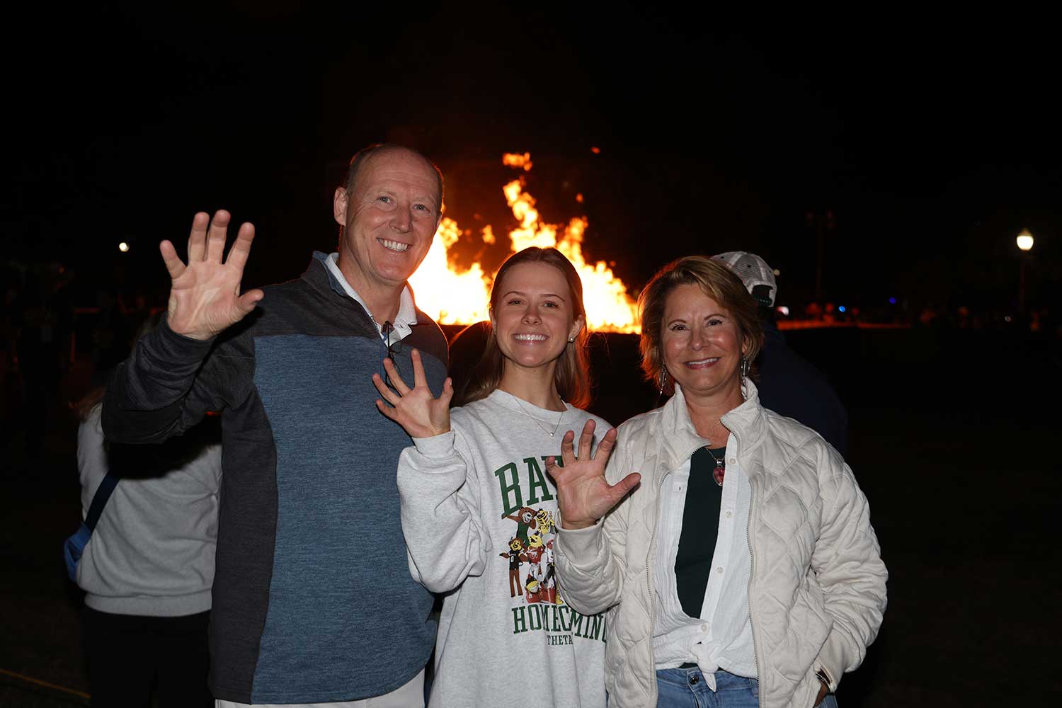A Baylor family at the bonfire with the hand sign for Sic' Em