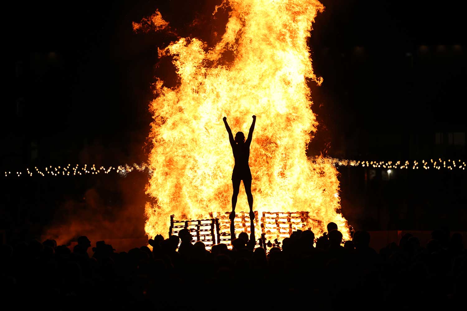 A girl highlighted in front of the bonfire